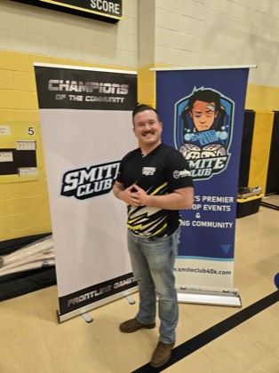 Golden Ticket winner Tanner Floyd poses between the Smite Club and Champions of the Community banners at Scorched Earth Open 2026