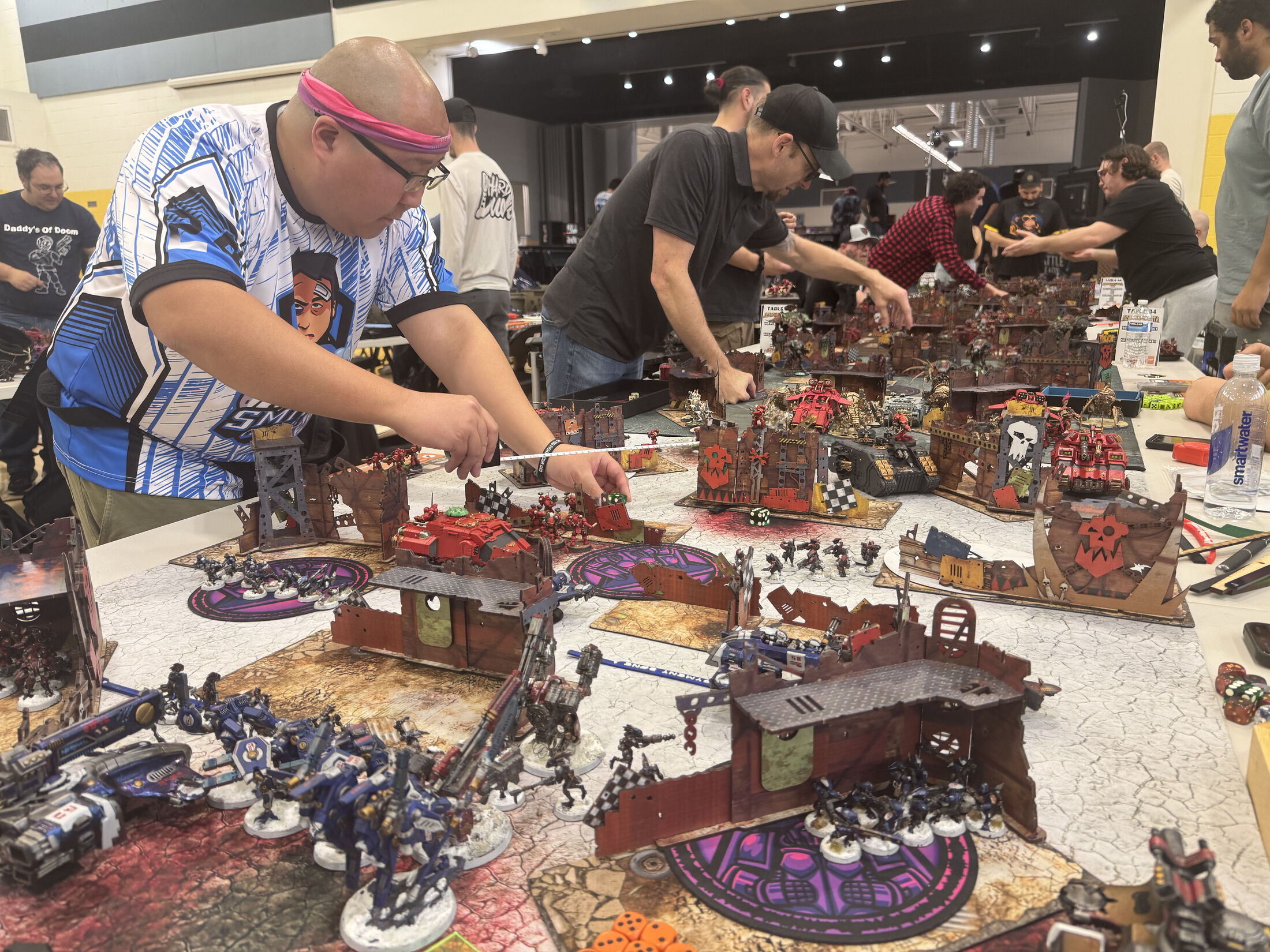 A Smite Club player measures movement across a crowded Warhammer table